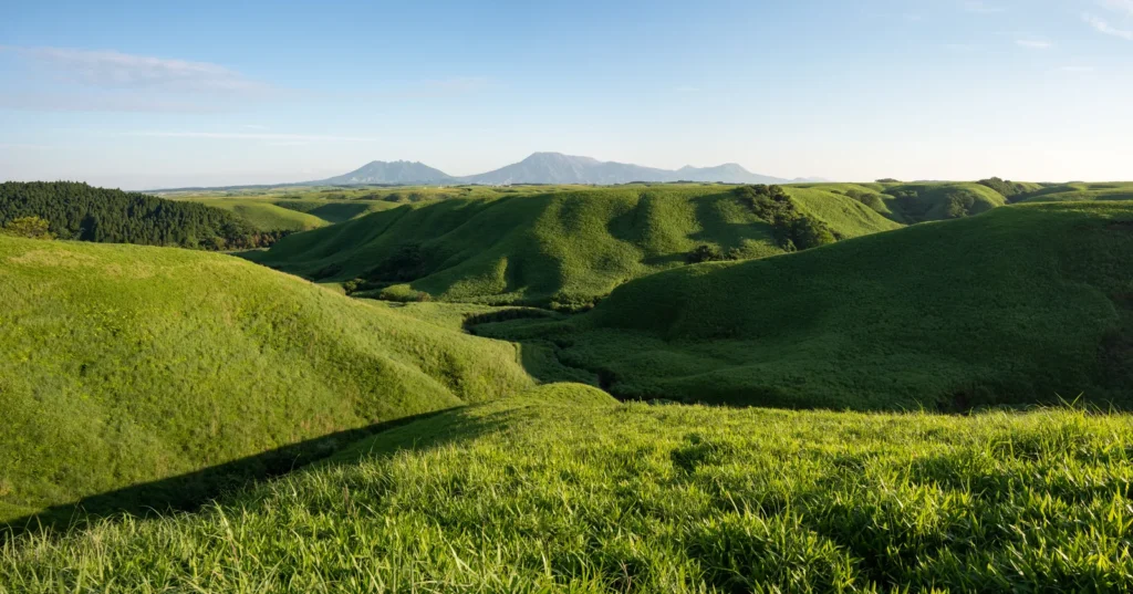 Rolling green grassland inside the Aso caldera with the central peaks on the horizon