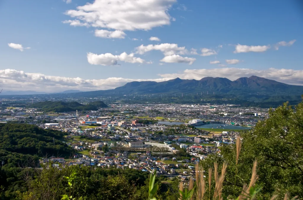 Broad volcanic ridge of Mount Akagi rising beyond a town spread across the plain, Gunma
