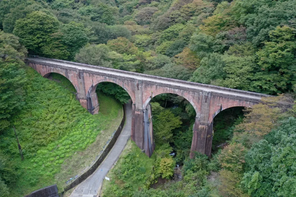 Red brick arched railway viaduct spanning a forested valley at Usui Pass, Gunma