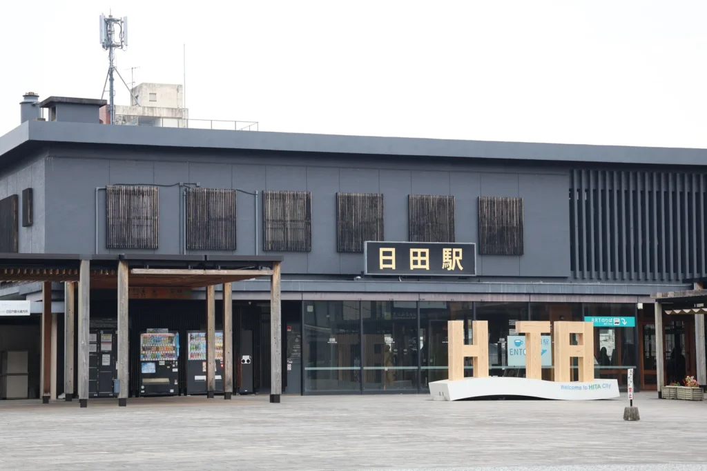 Dark timber-clad station building and open forecourt at Hita Station, Oita