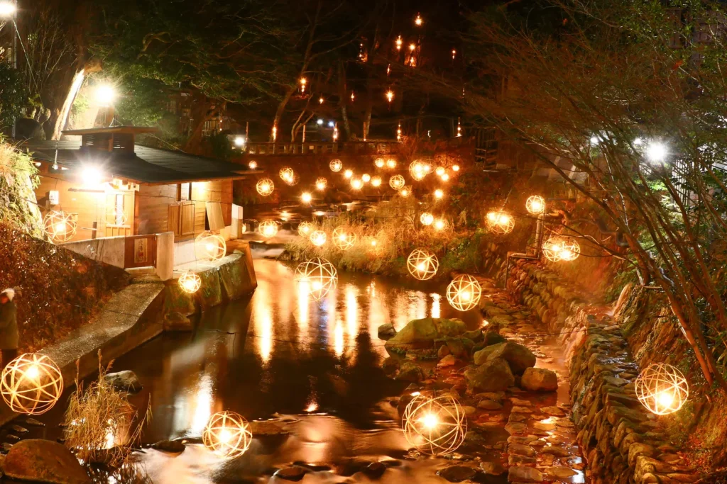 Round lanterns lit above the river at Kurokawa Onsen at night