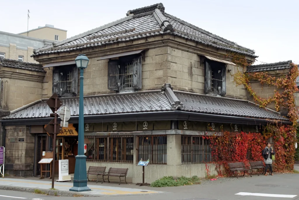 The two-storey Former Natori Takasaburo Store in Otaru, now a glass shop, with tiled roofs and autumn ivy