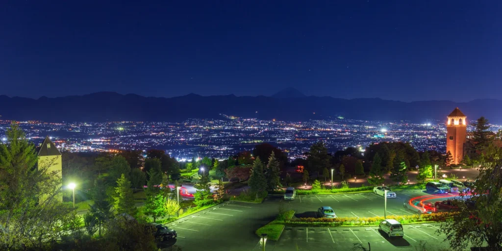 The lights of the Kofu basin at night seen from Fuefukigawa Fruit Park, with Mount Fuji on the skyline
