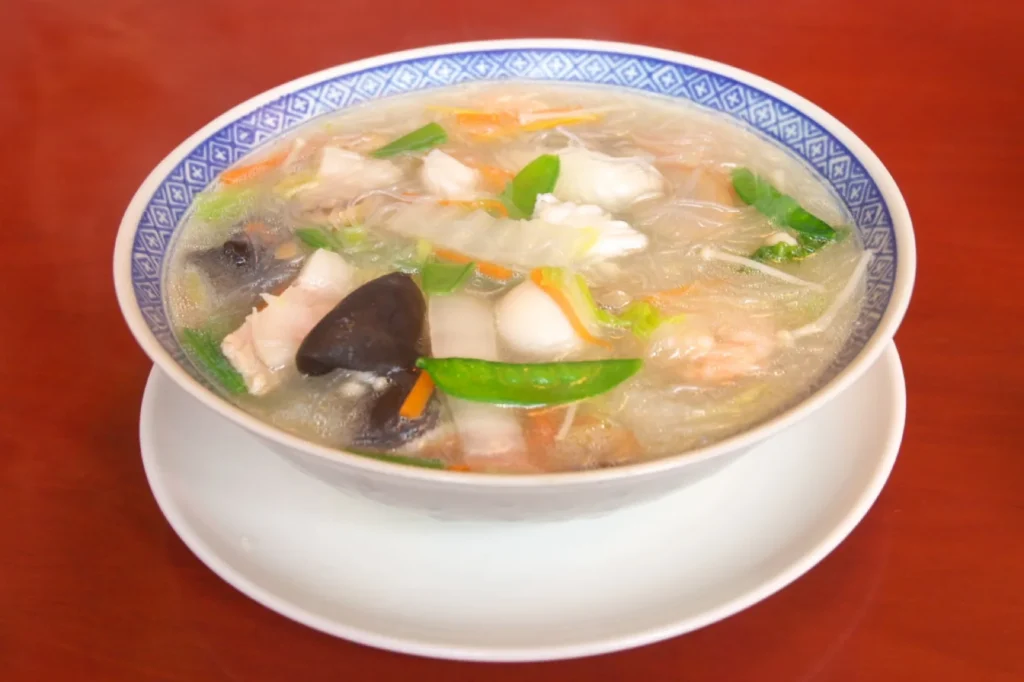 A bowl of taipien, a clear soup with glass noodles, seafood, pork and vegetables