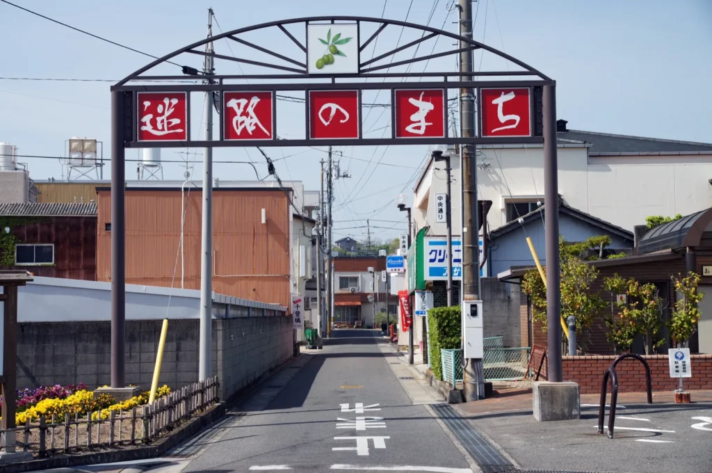 A red-lettered arch over a narrow street marking the entrance to Meiro-no-machi in Tonosho