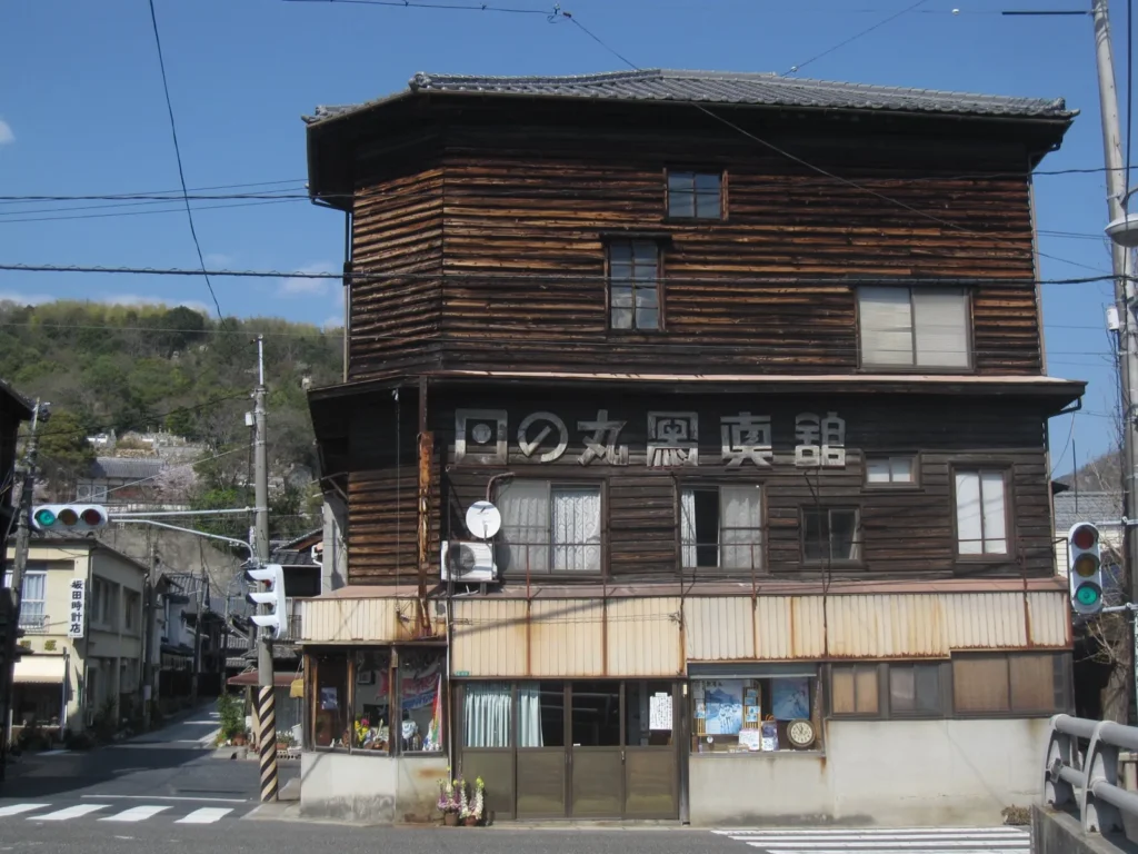 The three-storey timber front of the former Hinomaru photo studio on a street corner in Takehara, with its name in large letters